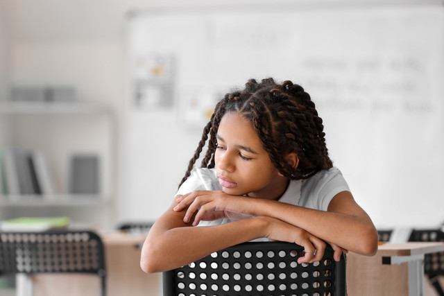 Student alone in classroom in a chair.