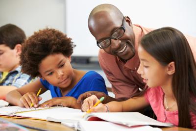Educator helping two students in a classroom.